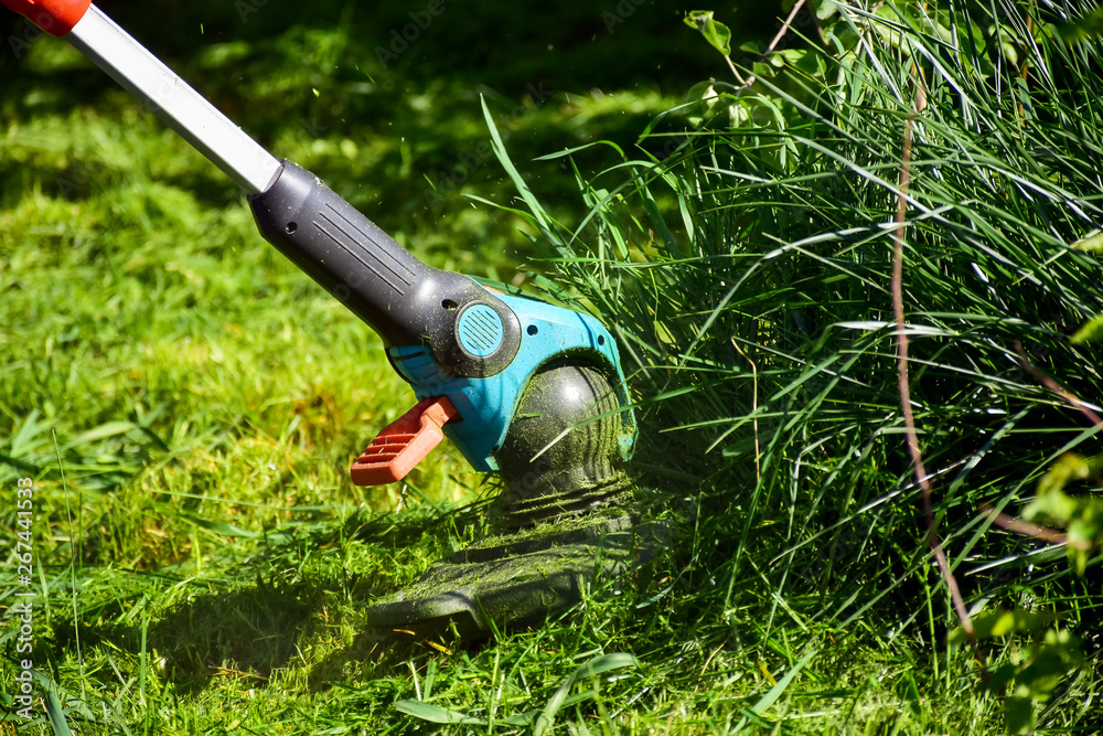 The simple mThoments of life, ordinary work in the garden -  man trimming grass with heavy-duty trim