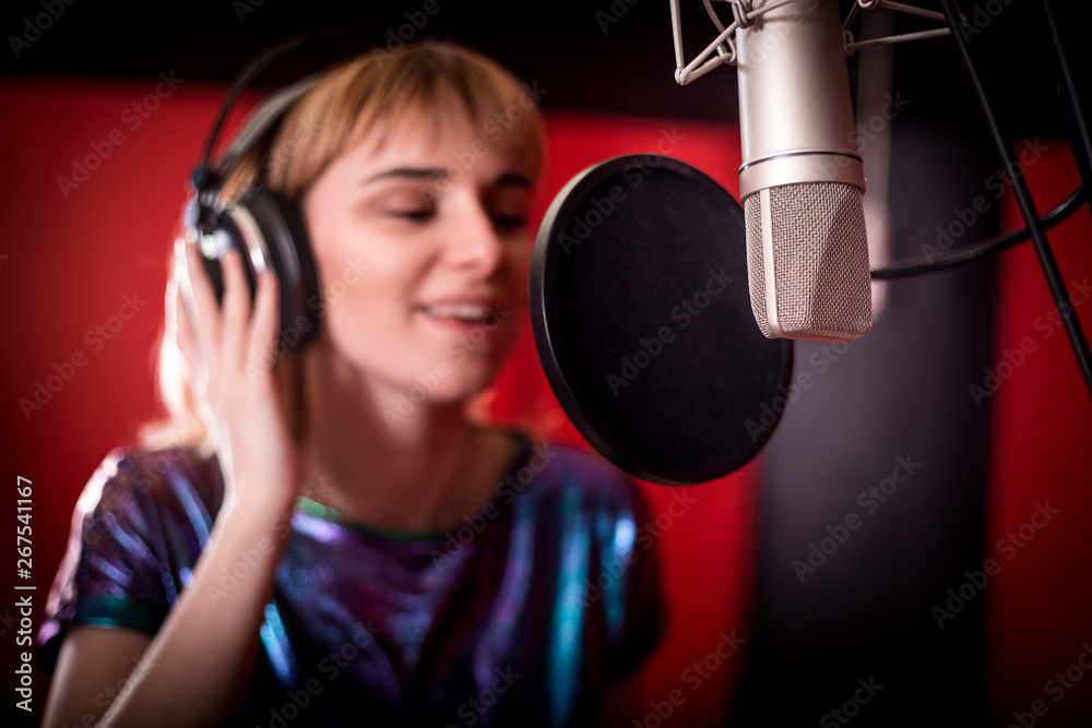 Young singer woman during music session at recording studio