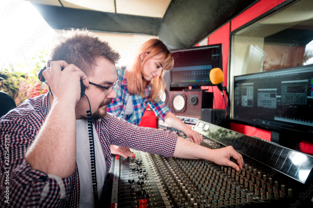 Music engineer and musician working together in recording studio using mixing desk