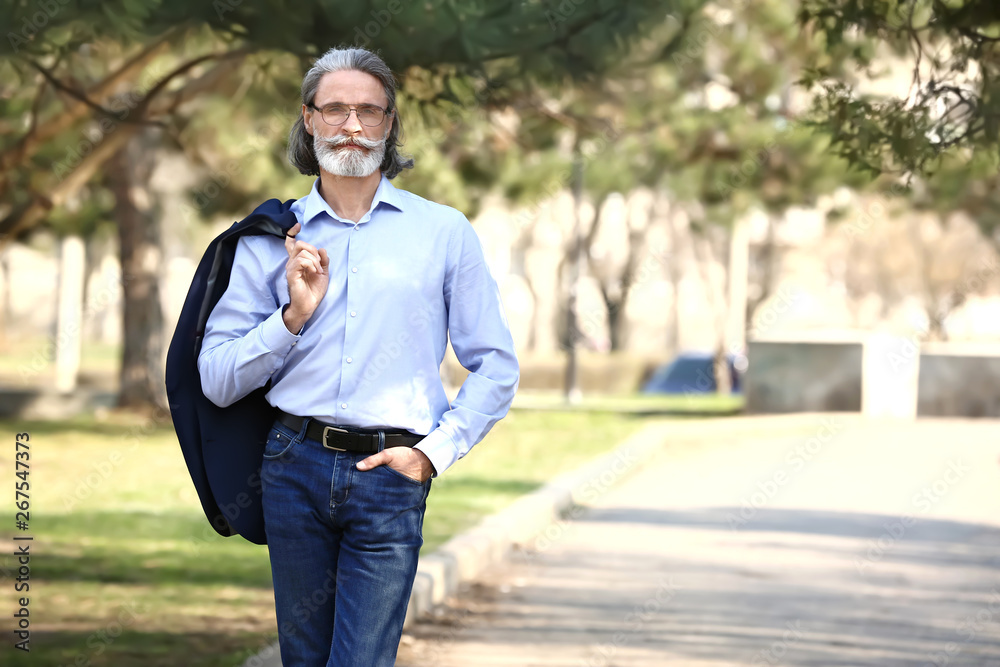 Portrait of handsome mature businessman in city park