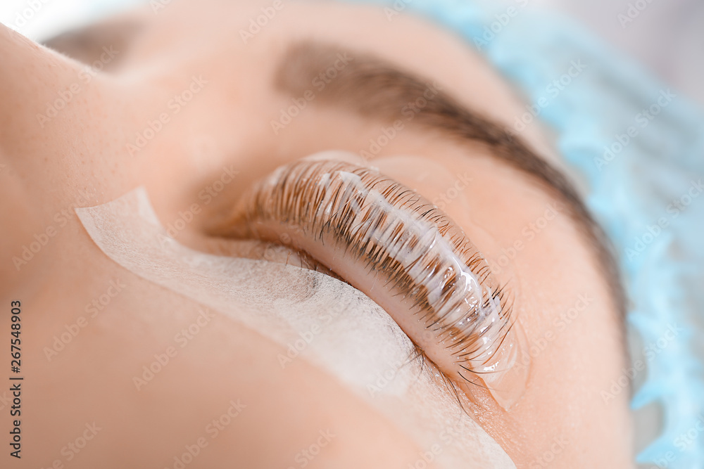 Young woman undergoing procedure of eyelashes lamination in beauty salon, closeup