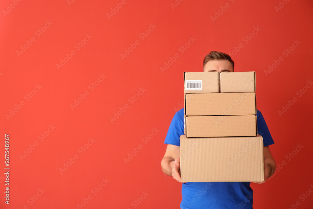 Delivery man with boxes on color background