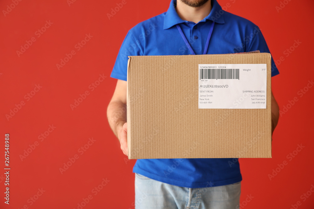 Delivery man with box on color background