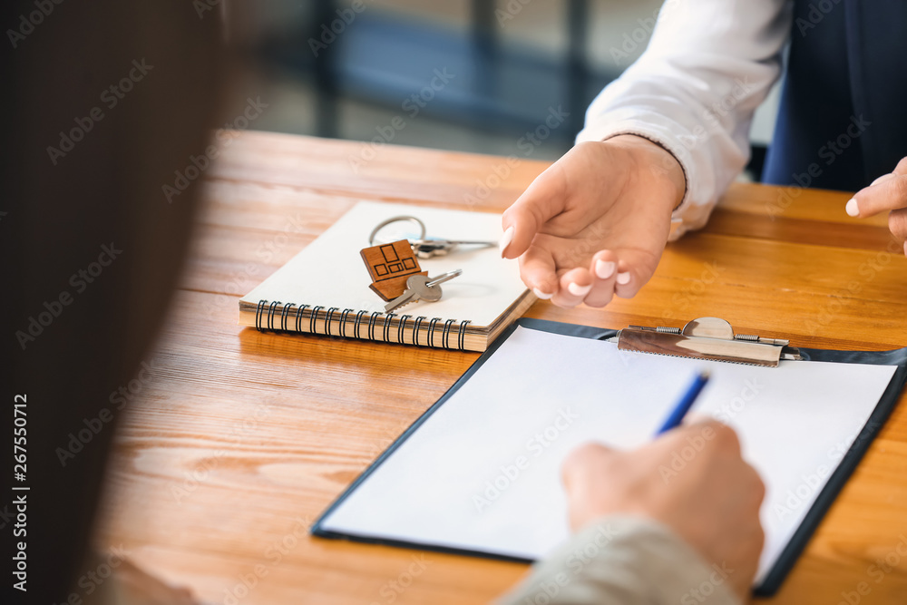 Young man signing a contract in office of real estate agent