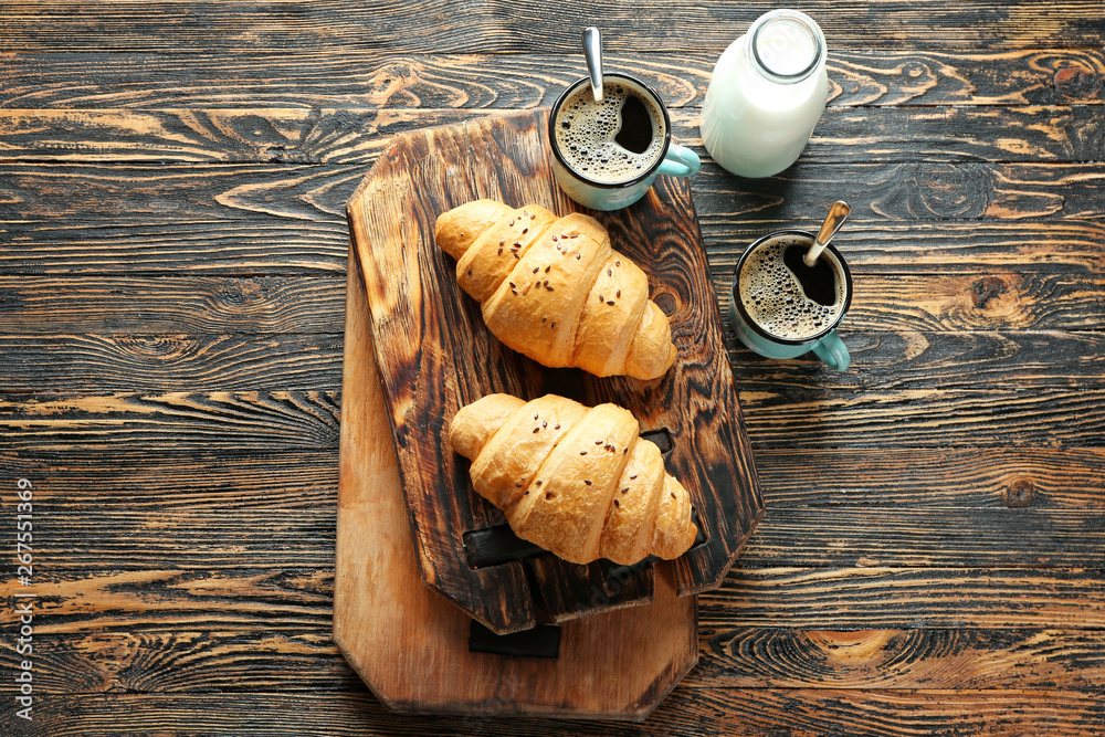 Tasty croissants with coffee on wooden table