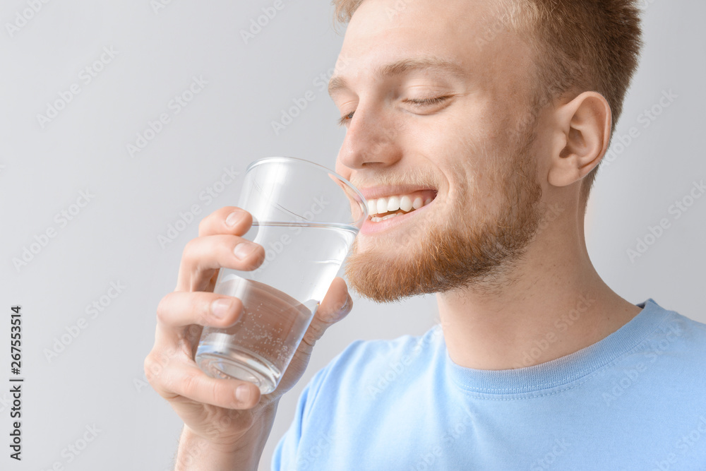 Man with glass of fresh water on light background