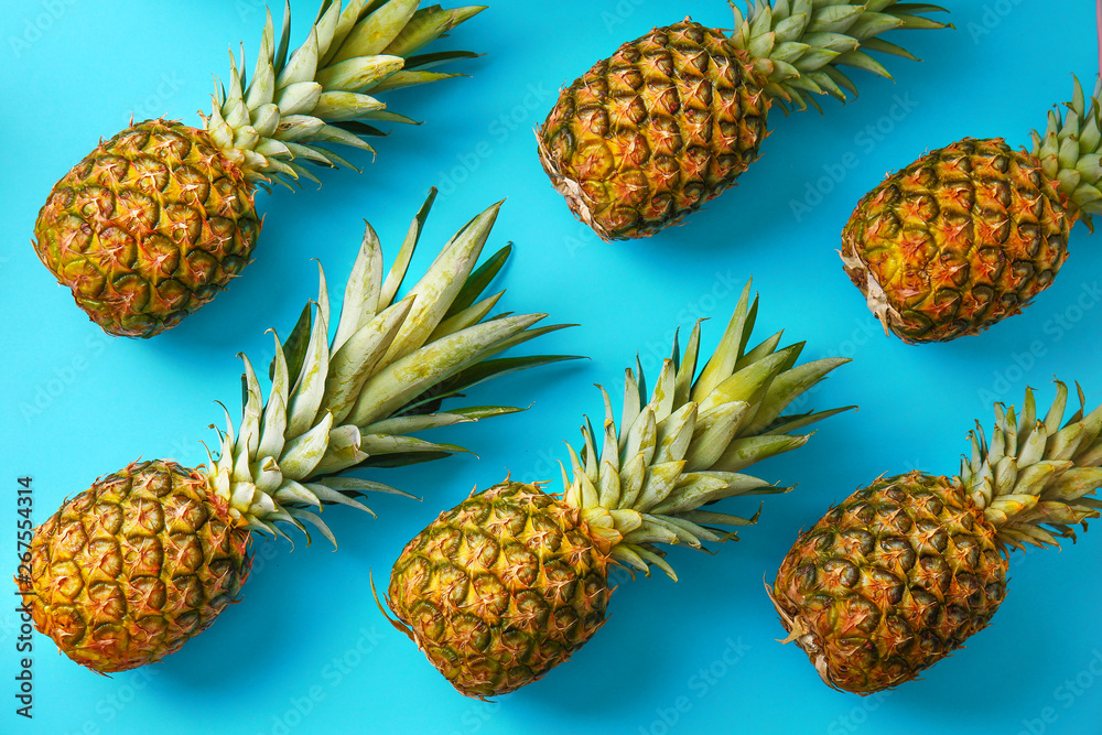 Many ripe pineapples on color background