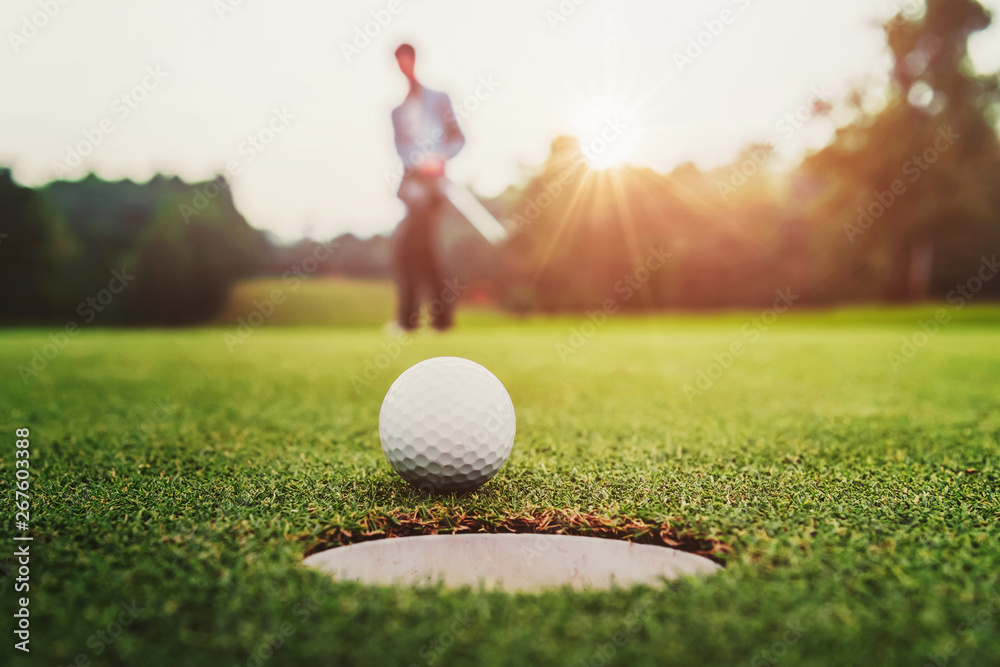 golf player putting golf ball into hole