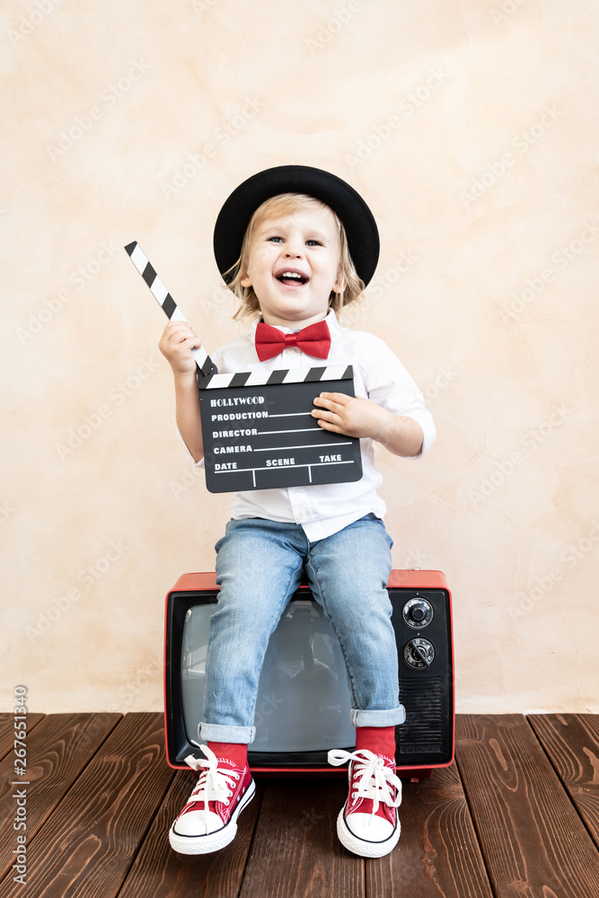 Child with clapper board playing at home.