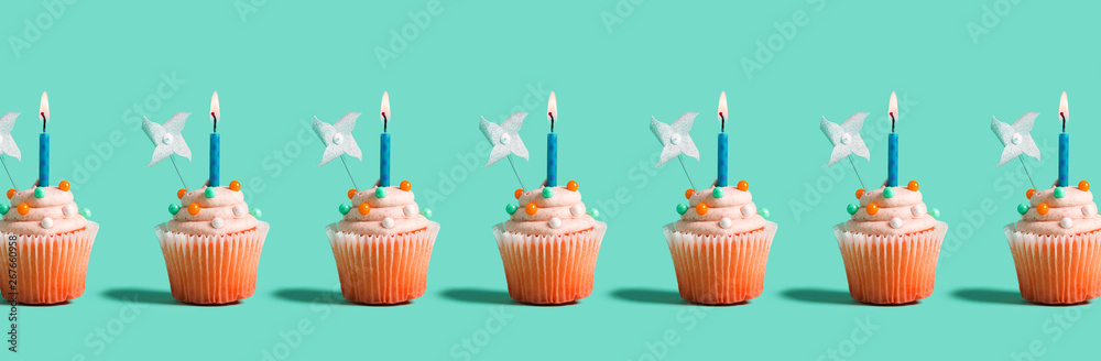 Tasty celebratory cupcakes with decorative lit candles