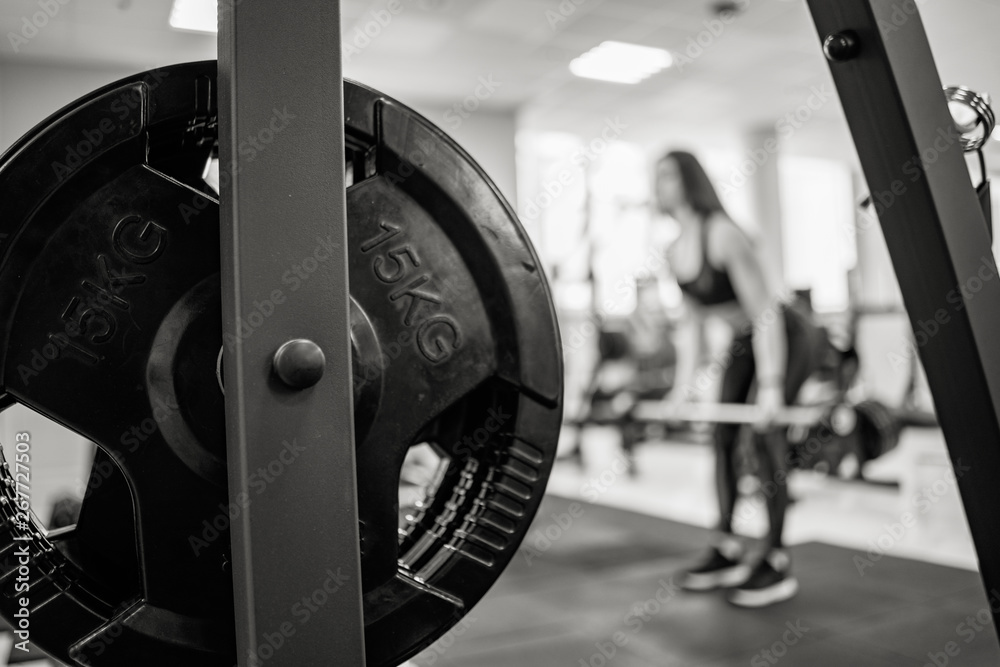 Iron barbell disk on the background of a woman training in the gym. Fifteen kg on the barbell disk. 