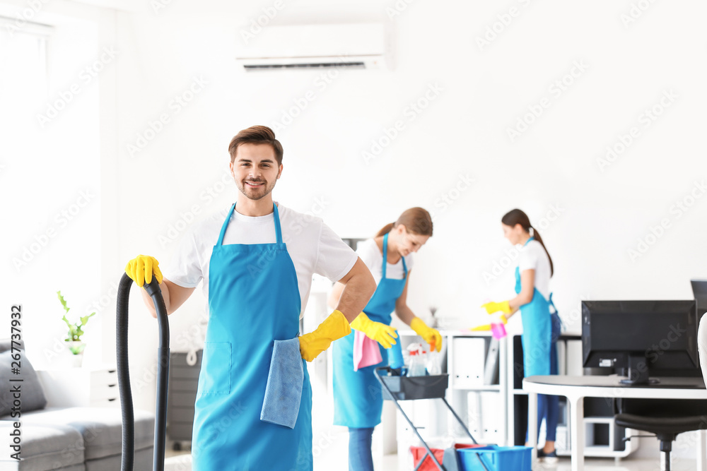 Janitor with vacuum cleaner in office