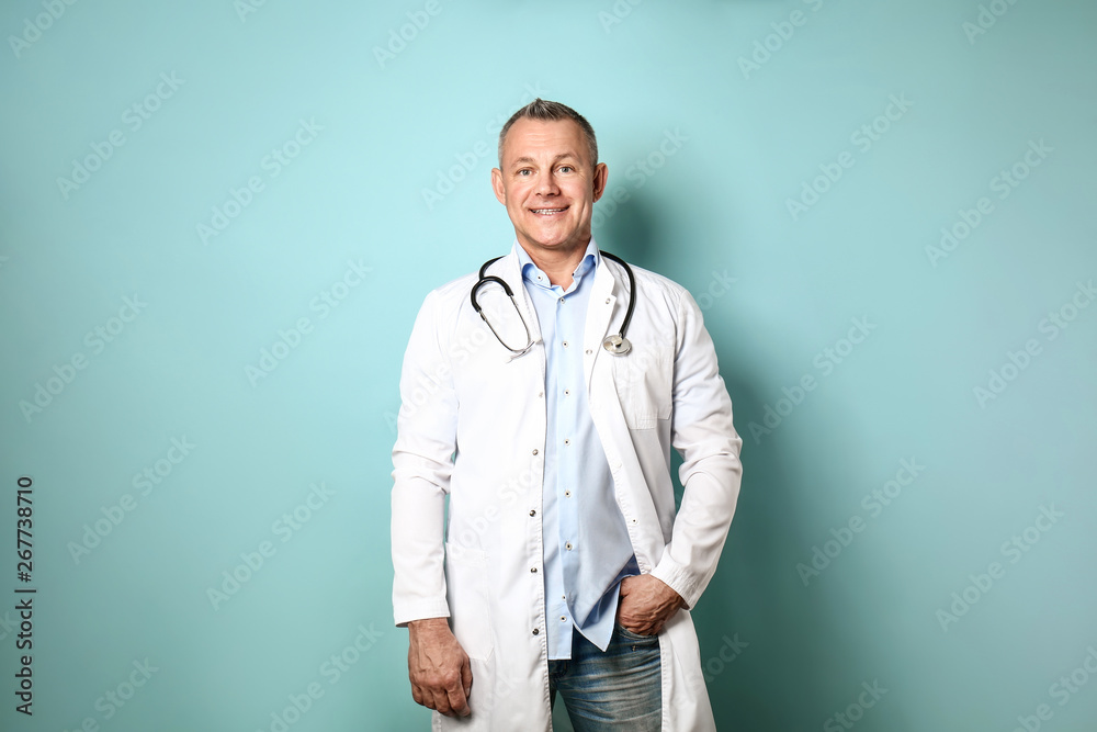 Handsome middle-aged doctor on color background