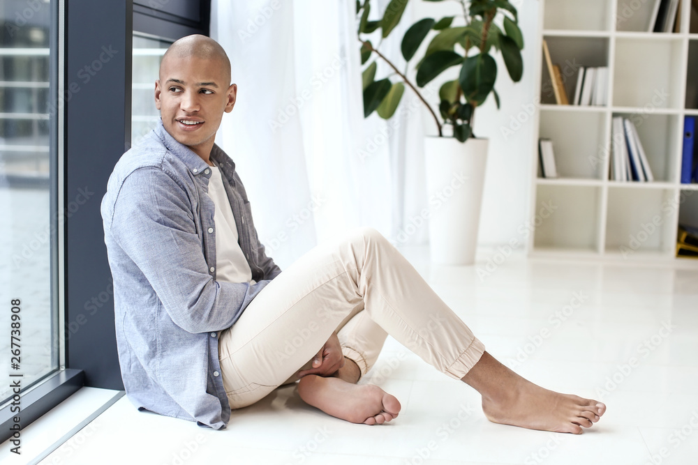 Handsome African-American man sitting near window at home