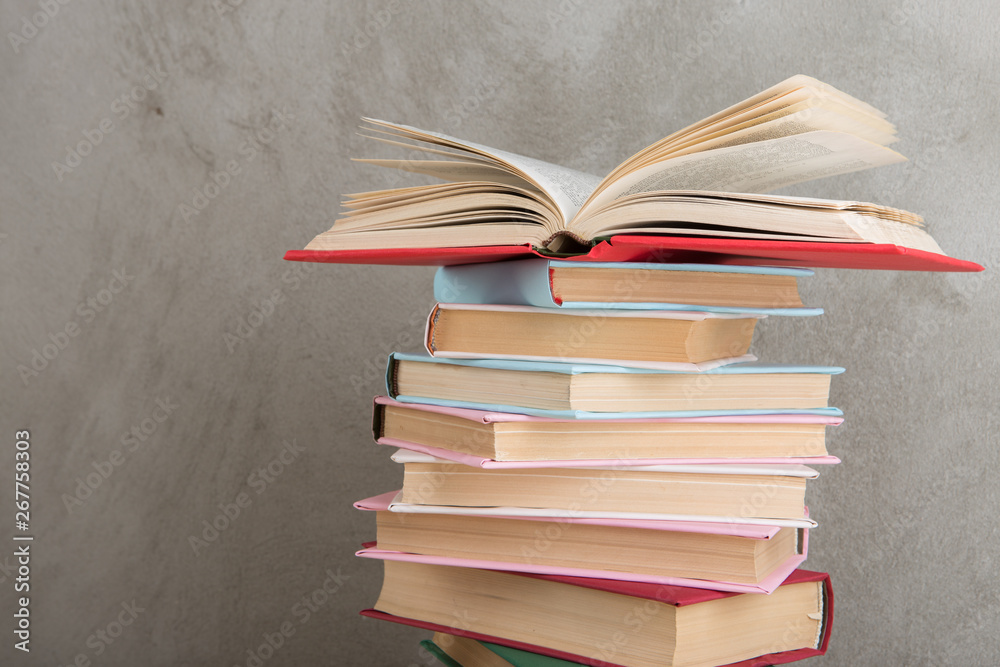 Education and reading concept - group of colorful books on the wooden table, concrete wall blackboar