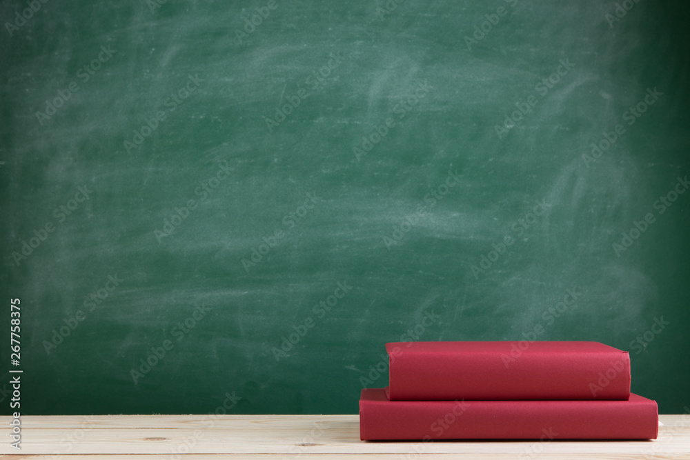 Education and reading concept - group of colorful books on the wooden table in the classroom, blackb