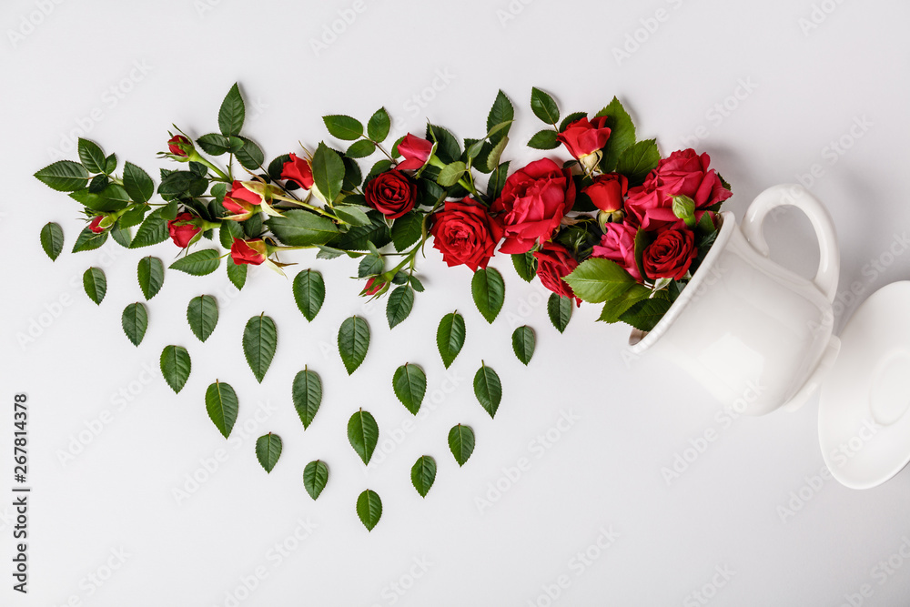 Creative layout made of coffee or tea cup with red roses on white background