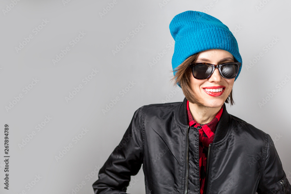  Fashion photo of stylish young woman in jacket, jeans, plaid shirt wearing sunglasses