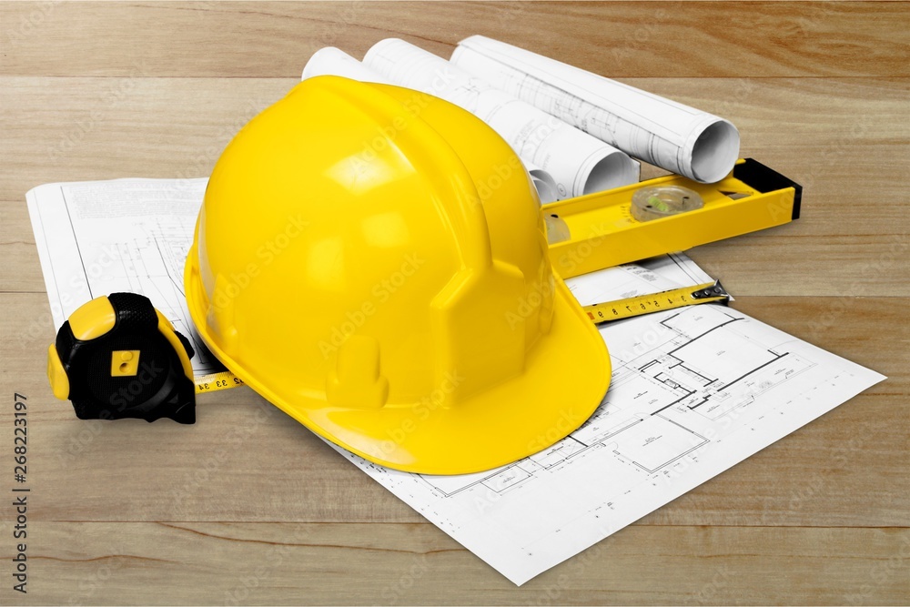 Yellow hard hat and blueprints on wooden