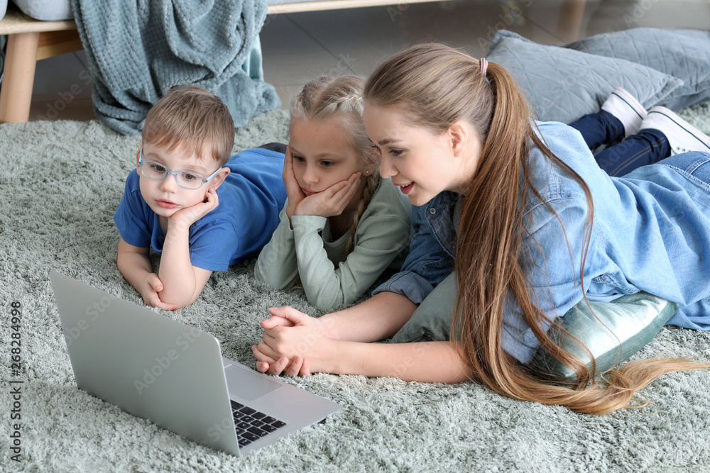 Young mother with little children watching cartoons at home