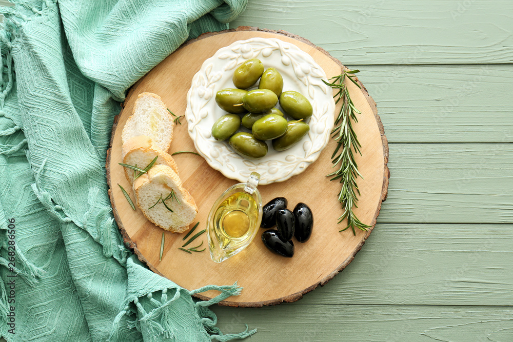 Tasty olives with oil and bread on wooden table