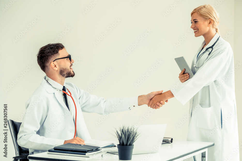 Doctor at the hospital giving handshake to another doctor showing success and teamwork of profession