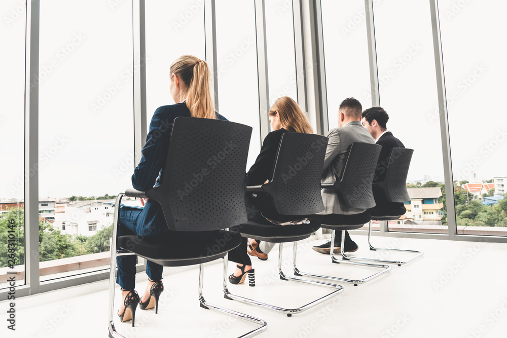 Businesswomen and businessmen waiting on chairs in office for job interview. Corporate business and 