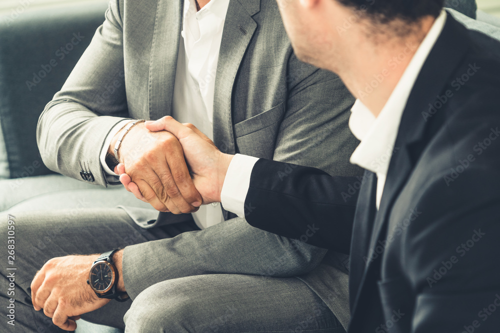 Businessman handshake with another businessman partner in modern workplace office. People corporate 