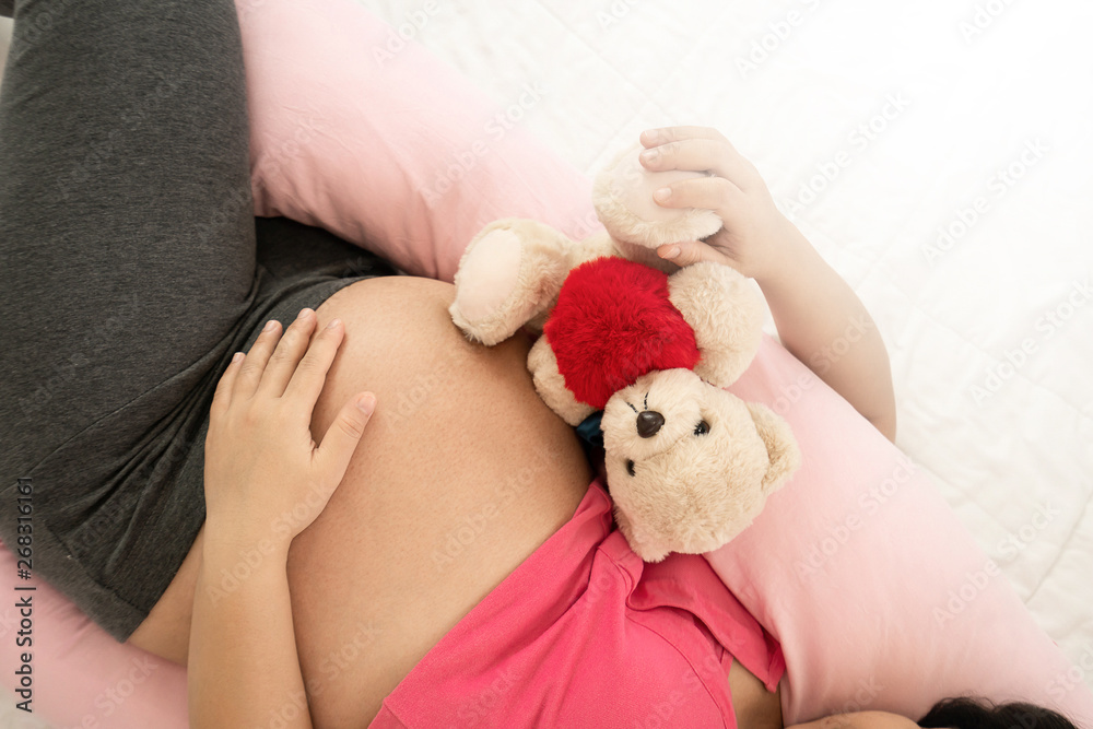 Happy pregnant woman sleeping on bed in bedroom at home for resting and stress relief. The young exp