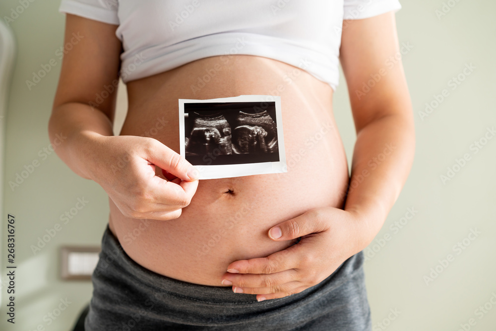 Pregnant woman feeling happy at home while taking care of her child. The young expecting mother hold