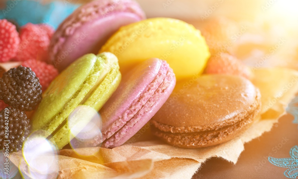 Delicious colorful macaroons with berries on parchment paper