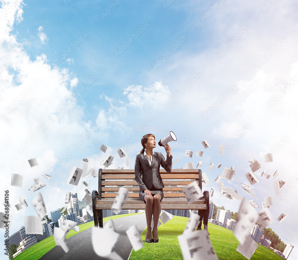 Business woman with megaphone on wooden bench