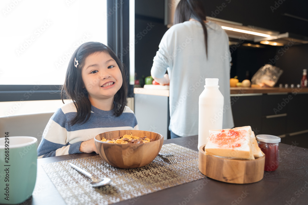 妈妈和女儿在厨房吃牛奶麦片早餐。