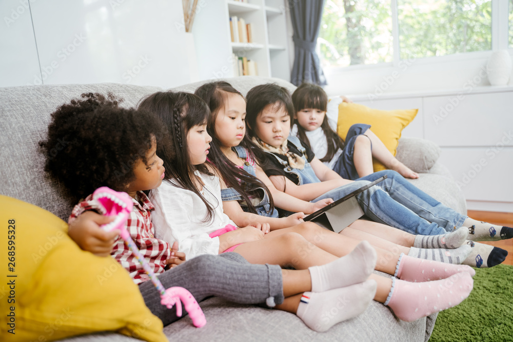 一群小孩子一起在数字平板电脑上看电影、电影和动画片。孩子们在玩t