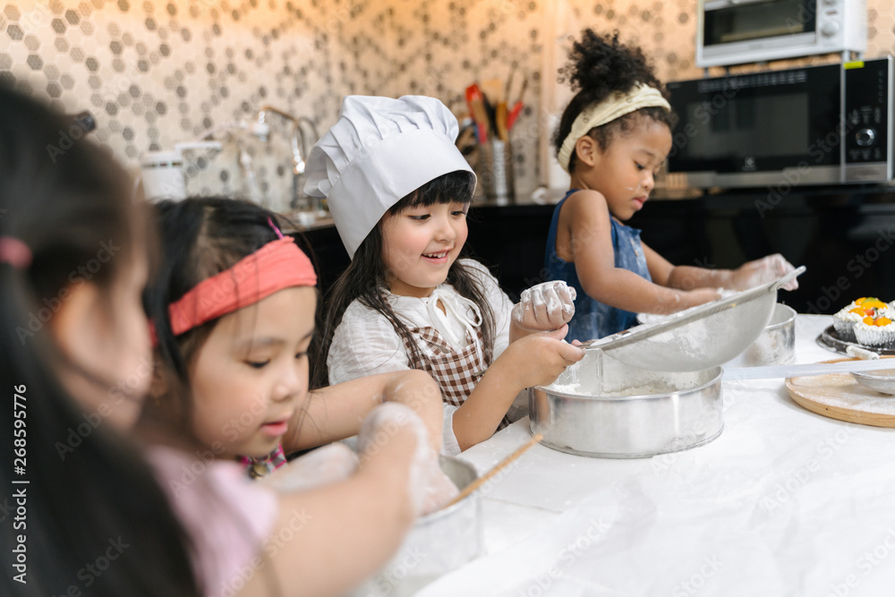 Group of kids are preparing the bakery in the kitchen .Children learning to cooking cookies