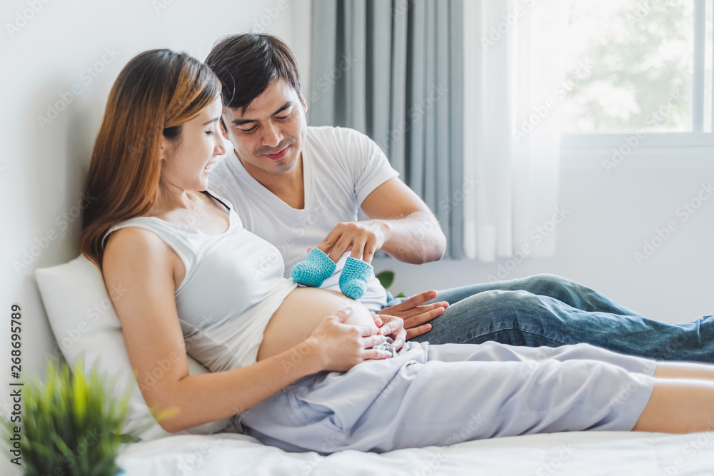 Young Asian husband  playing with his pregnant wife on white bed with happy and smile