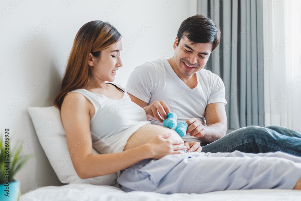 Young Asian husband  playing with his pregnant wife on white bed with happy and smile