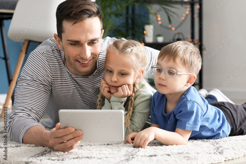 Young father with little children watching cartoons at home