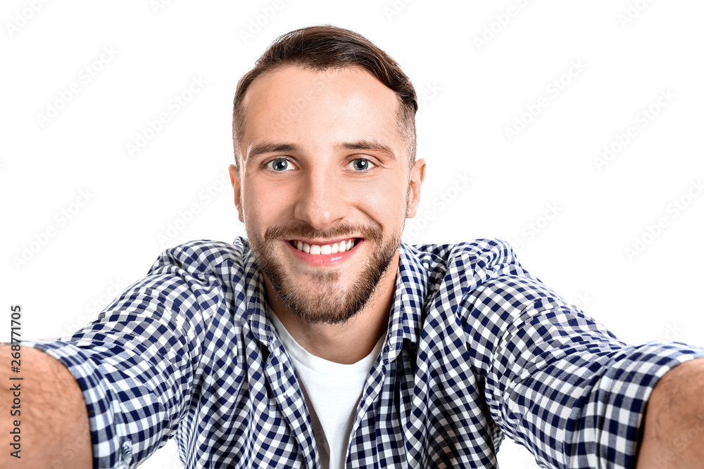 Portrait of handsome man taking selfie on white background