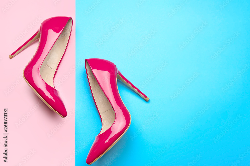 Stylish high heeled shoes on color background