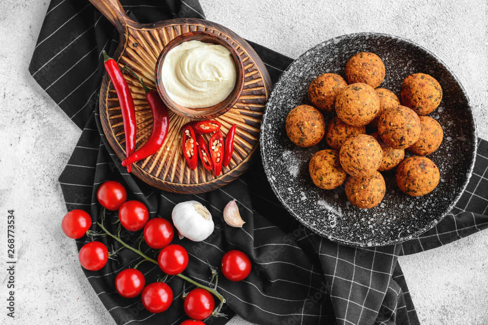 Plate with tasty falafel balls and sauce on light table