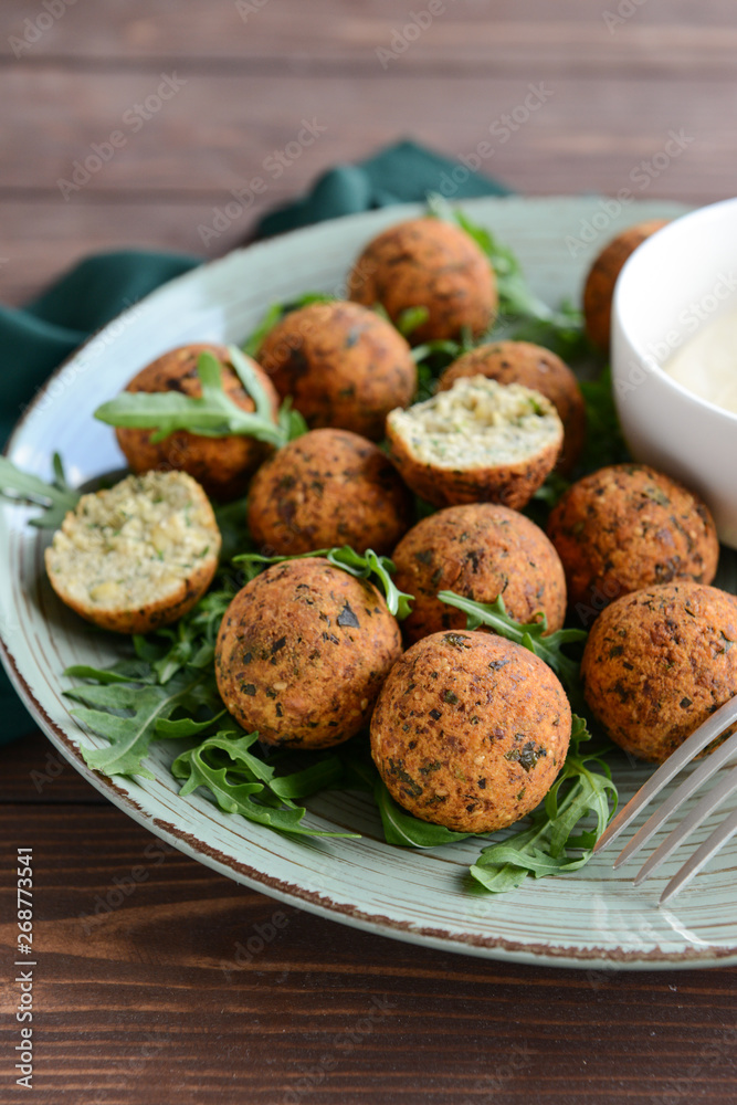 Plate with tasty falafel balls on wooden table, closeup