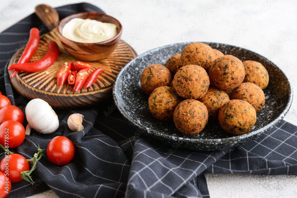 Plate with tasty falafel balls and sauce on light table