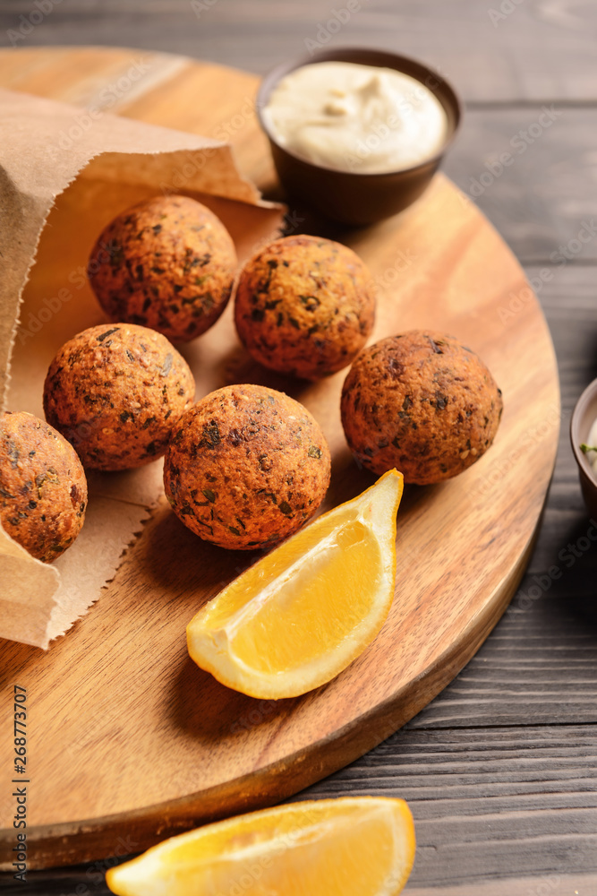 Board with tasty falafel balls on wooden table