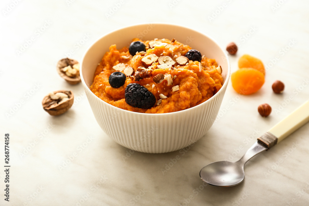 Bowl with mashed sweet potato, nuts and berries on table