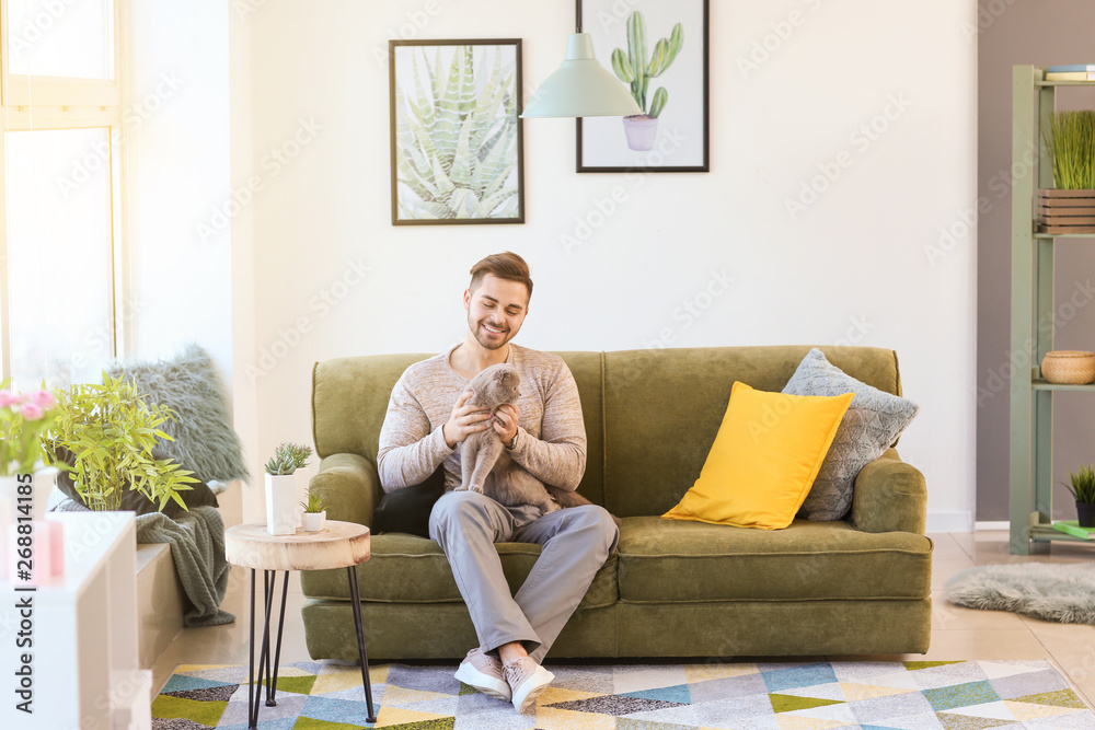 Young man with cute funny cat at home