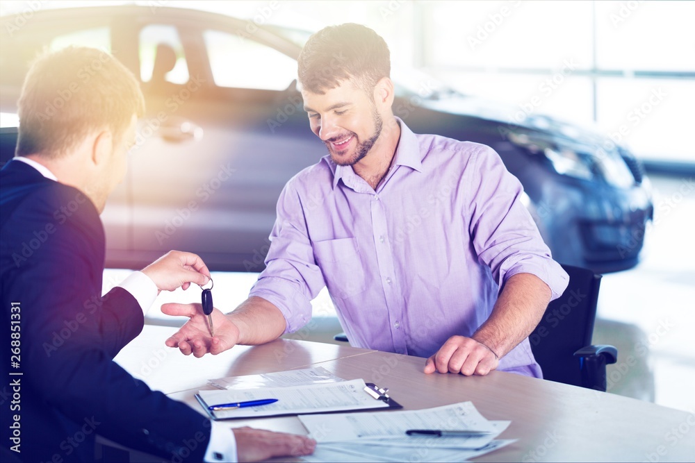 Happy man with car dealer in auto show or salon