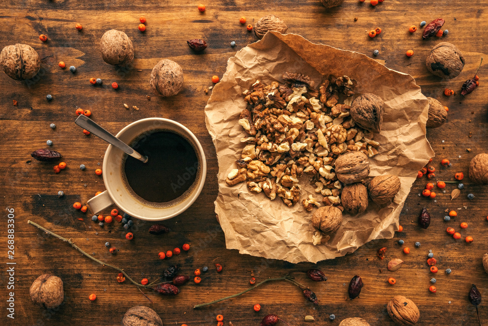 Ripe walnut fruit and coffee cup on table, top view