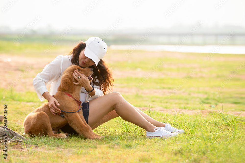 快乐漂亮的亚洲女人和她的狗金毛寻回犬一起在户外玩耍，生活方式t