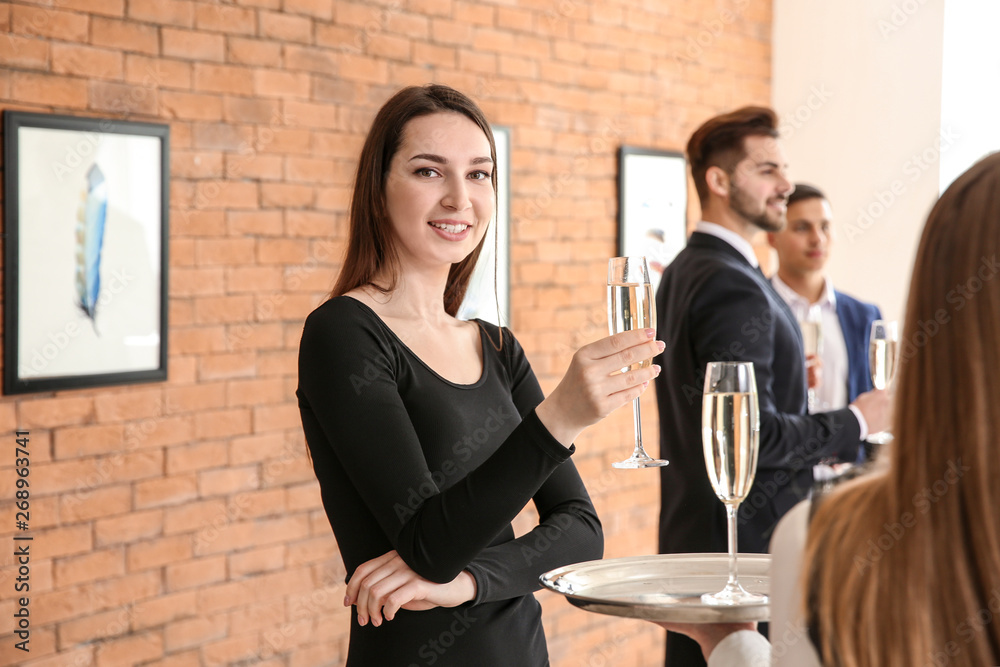 Woman drinking champagne at exhibition in modern art gallery